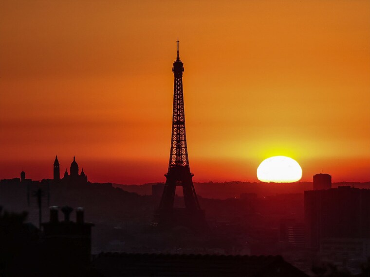 The sun rises by the Eiffel Tower and the Sacre Coeur Basilica ontop of the Montmartre hill in Paris on July 1, 2025, as the city is on red alert for high temperatures, with the top of the Eiffel Tower shut, polluting traffic banned and speed restrictions in place as a searing heatwave gripped Europe. Scientists say human-induced climate change is making such heatwave events more intense, frequent and widespread. Temperatures in France were expected to hit a peak today, according to the Meteo France weather agency, with the highest extreme heat warning in place in 16 departments across the country.