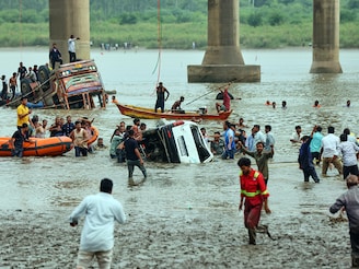 Rescuers and locals look for survivors after several vehicles fell into a river following the collapse of a portion of a bridge in Mujpur near Vadodara in the Indian state of Gujarat, Wednesday, July 9, 2025.