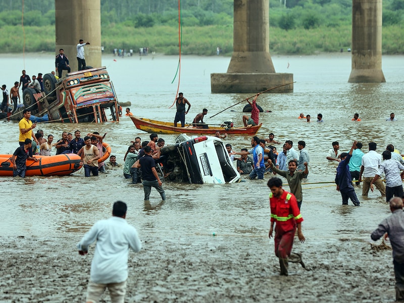 Rescuers and locals look for survivors after several vehicles fell into a river following the collapse of a portion of a bridge in Mujpur near Vadodara in the Indian state of Gujarat, Wednesday, July 9, 2025.