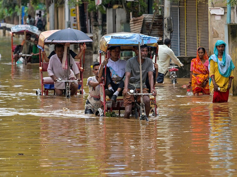 Residents commute on cycle rickshaws through floodwaters after heavy monsoon rains in Guwahati, Assam, on July 22, 2025.