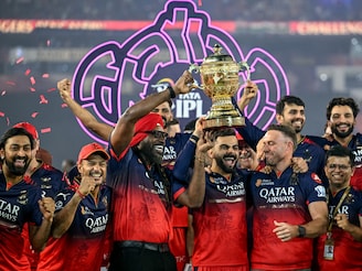 Royal Challengers Bengaluru"s Virat Kohli (C), along with his former teammates AB de Villiers (centre R) and Chris Gayle (centre L), celebrates with the trophy after winning the final match of the Indian Premier League (IPL) Twenty20 against Punjab Kings at the Narendra Modi Stadium in Ahmedabad on June 4, 2025.