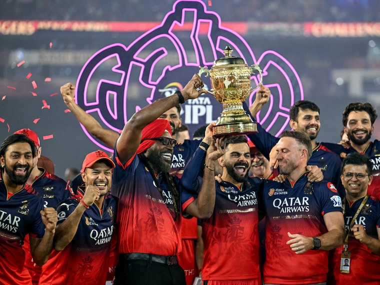 Royal Challengers Bengaluru"s Virat Kohli (C), along with his former teammates AB de Villiers (centre R) and Chris Gayle (centre L), celebrates with the trophy after winning the final match of the Indian Premier League (IPL) Twenty20 against Punjab Kings at the Narendra Modi Stadium in Ahmedabad on June 4, 2025.