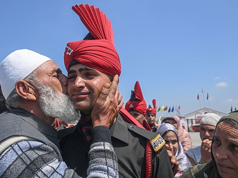 A father of a newly recruited Indian army soldier from the Jammu and Kashmir Light Infantry (JAKLI) kisses his son after a passing-out parade at the JAKLI army headquarters in Srinagar on June 5, 2025.