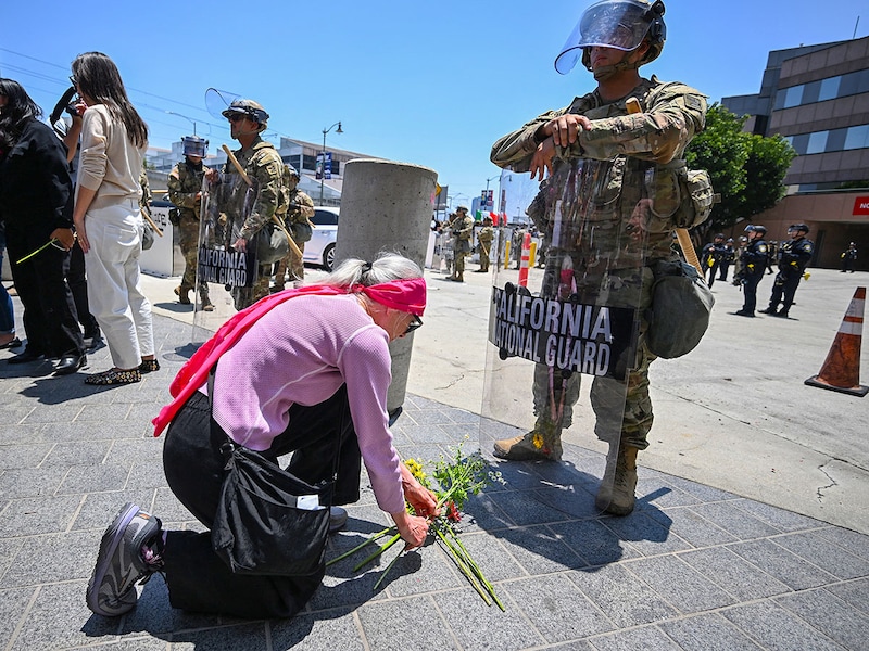 Members of the clergy and other protestors place flowers at the feet of a California National Guardsman stationed outside federal buildings near the Metropolitan Detention Center in Los Angeles on June 10, 2025, amid ongoing protests in response to federal immigration operations. US President Donald Trump on June 10 claimed Los Angeles was being invaded by a "foreign enemy" and vowed to "liberate" the city after days of protests sparked by immigration raids. Trump has deployed thousands of troops, including 700 active duty US Marines, to Los Angeles, despite California authorities saying the move is unnecessary and will inflame the situation.