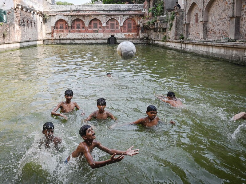 Local boys cool themselves at the Hazrat Nizamuddin Baoli, a heritage-era water tank, on a scorching summer afternoon in New Delhi on June 13, 2025. A heatwave with a "feels-like" temperature of 51 deg C caused the Indian Meteorological Department to declare a red alert warning. Relief is underway as an early monsoon is expected this weekend, ten days before schedule.