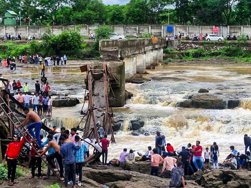 People stand near an iron bridge over the Indrayani river after it collapsed, in Pune district, Maharashtra, Sunday, June 15, 2025. Some people are feared to have been swept away after the collapse.
