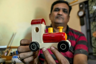 Artisan Kouser Pasha displaying a wooden toy train at his toy factory in Channapatna in the Ramanagara district of India"s Karnataka state. India"s town of Channapatna is famed for its wood and lacquer toys, carved from ivory wood from a local deciduous tree and dipped in brightly coloured dye from natural ingredients including turmeric and indigo. Image: Idrees Mohammed/AFP