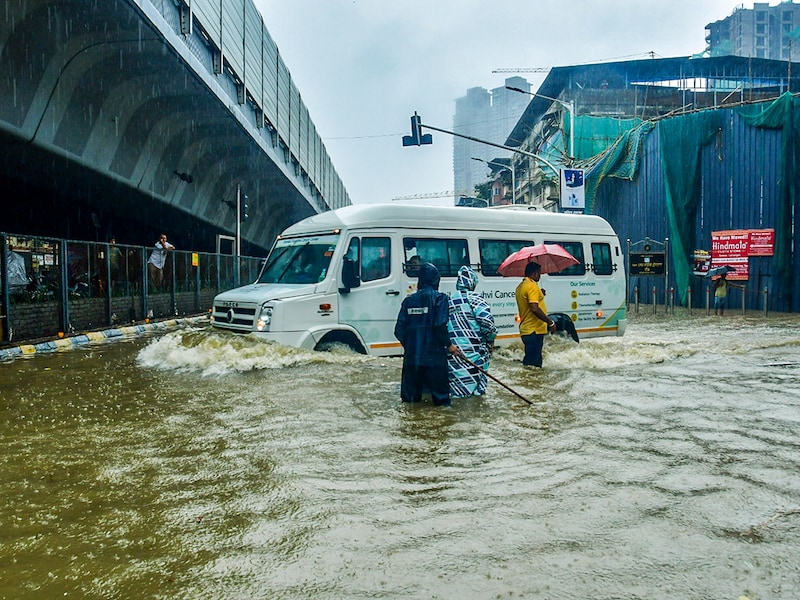 Commuters wade through an inundated road amid rains in Mumbai on May 26, 2025. A record 104 mm of rainfall lashed this region in just an hour this morning, signalling a cloudburst over South Mumbai. This caused the India Meteorological Department to upgrade its weather forecast for the day from a yellow to an orange alert, indicating the possibility of intense rainfall. The alert now covers Mumbai, Thane, and Raigad districts.