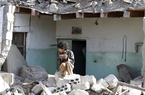  A boy sits at the site of an air strike in a residential area near Sanaa Airport on March 26. Saudi Arabia and Gulf region allies launched military operations, including air strikes in Yemen, to counter Iran-allied forces besieging Aden where the US-backed Yemeni president had taken refuge <br />