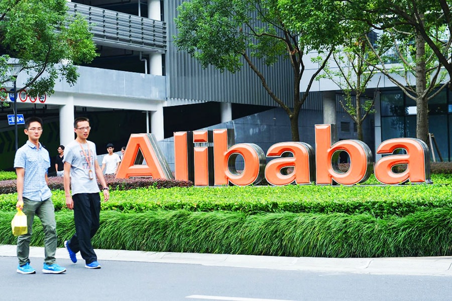 Staff members walk past a logo of Chinese ecommerce giant Alibaba at its headquarters in Hangzhou in China's eastern Zhejiang province. Image: AFP / China Out 