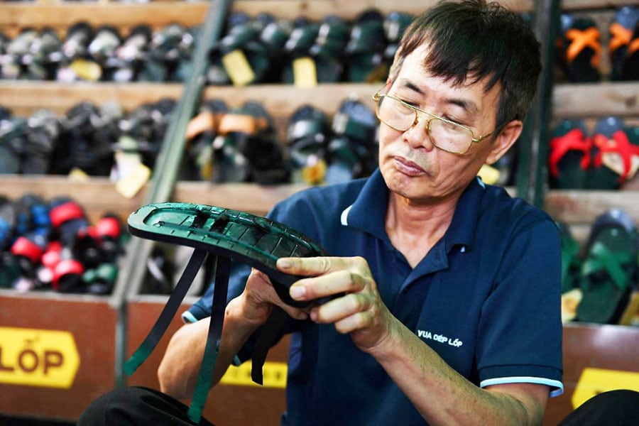 This photo taken on July 5, 2022, shows a worker making rubber sandals at a shop in Hanoi. Made from recycled military truck or aircraft tyres, Vietnam's hand-made rubber sandals, the famously rugged footwear of the Viet Cong, have travelled vast distances over the decades. Image: Nhac Nguyen/AFP 