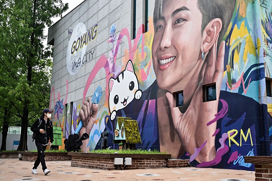 A man walks past a mural depicting RM, a member of K-pop group BTS, in Goyang, northwest of Seoul, on June 15, 2022. (Photo by Anthony WALLACE / AFP)