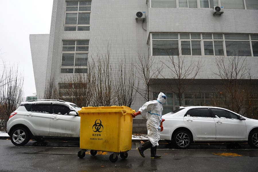 In this file photo taken on February 14, 2020, a worker carts a bin loaded with medical waste at the Youan Hospital in Beijing. Hazmat-suited workers poke plastic swabs down millions of throats in China each day, leaving bins bursting with medical waste that has become the environmental and economic levy of a zero-Covid strategy. Image: Greg Baker / AFP