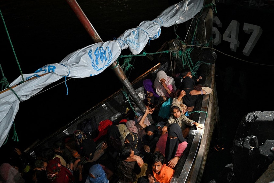 Rohingya refugees sit on a wooden boat after their were rescued by Indonesia's navy in the waters off Bireuen, upon their arrival to Krueng Geukueh port in Lhokseumawe, on the north coast of Aceh province on December 31, 2021. - Indonesia's navy rescued more than 100 Rohingya migrants traveling in a wooden boat, bringing them to safety early December 31, 2021 morning following pressure from locals. (Credit: CHAIDEER MAHYUDDIN / AFP)