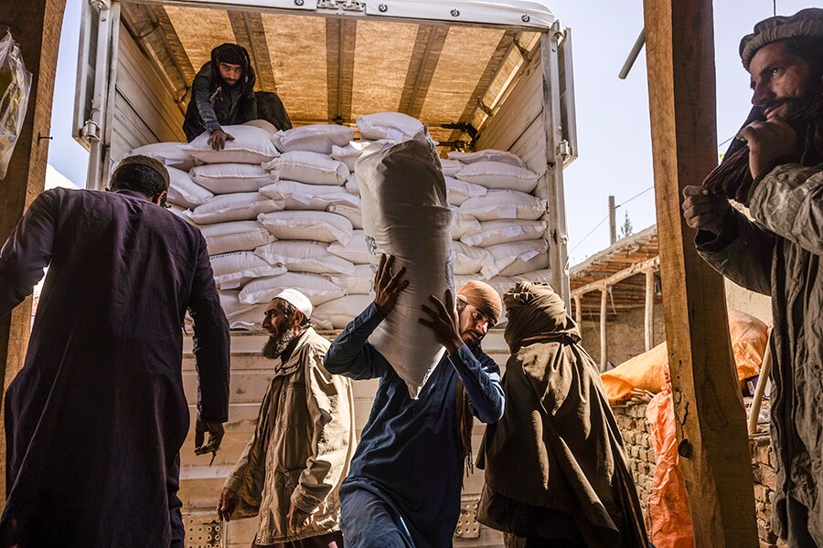 Laborers unload sacks of flour from a World Food Program convoy that traveled from Kabul to Afghanistan’s Tagab district, Oct. 27, 2021. Aid workers warn that a humanitarian crisis has already been exacerbated by the war in Ukraine, making it more difficult to feed the roughly 23 million Afghans — more than half the population — who do not have enough to eat. (Victor J. Blue/The New York Times)
