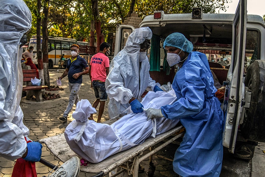 Workers transport the body of a person who died of COVID-19 in New Delhi on April 24, 2021. Nearly a third of excess deaths globally, some 4.7 million, took place in India. (Atul Loke/The New York Times) 