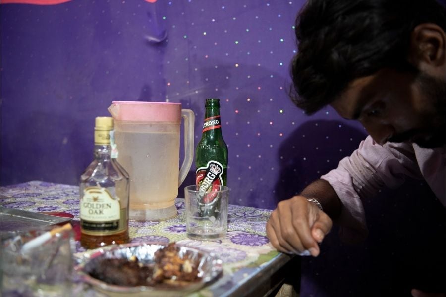 A man drinks Nepali-made alcohol in a mango orchard along the border with India, near Maruwai, Nepal, April 15, 2022. Since the Indian state of Bihar banned alcohol in 2016, a small industry of bars and restaurants has sprung up just across the border in Nepal, catering to Indians of all classes seeking to quench their thirst. Image: Saumya Khandelwal/The New York Times