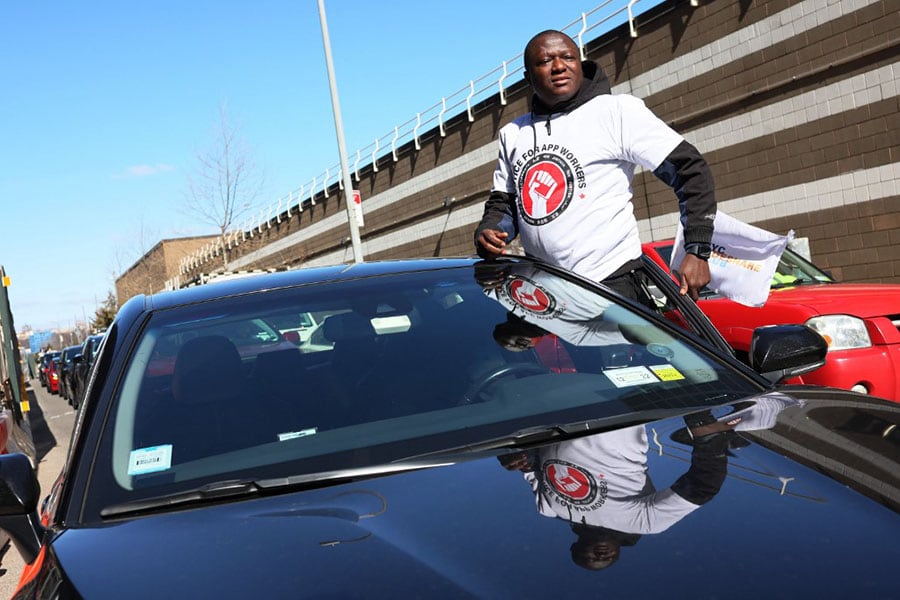 Mohammed Dukuly, a Lyft driver, hangs out of his car as he joins other app-based drivers and delivery workers take part in a protest at the former headquarters of Uber Technologies on March 29, 2022 in New York City, demanding fair pay in response to rising gas prices. Image: Michael M. Santiago/Getty Images/AFP 

