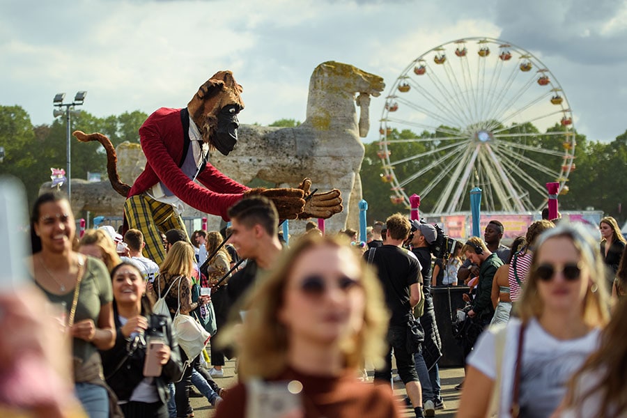 A showman manoeuvre an oversized figure in the form of a gorilla through the crowd at the Lollapalooza Festival in the Berlin Olympic Park; Photo by Gregor Fischer/picture alliance via Getty Images

