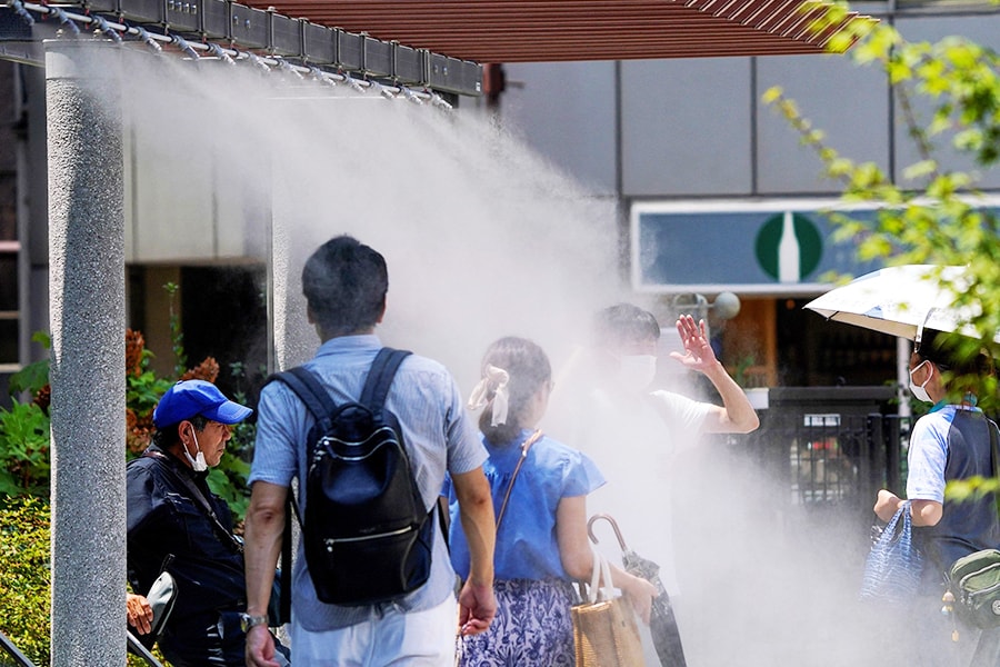 Pedestrians cool off in water mist during heatwave conditions in Tokyo on July 18, 2023.
Image: Kazuhiro Nogi / AFP 