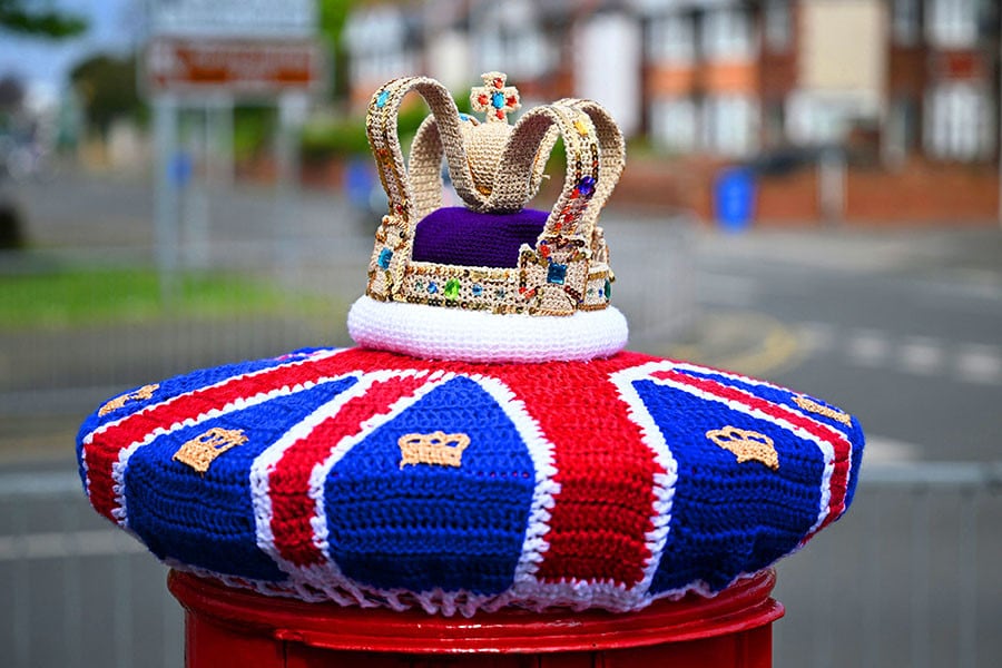 A photograph taken on May 2, 2023 shows a knitted crown displayed on a post office box next, in Rhyl, north Wales, ahead of the coronation ceremony of Charles III and his wife, Camilla, as King and Queen of the United Kingdom and Commonwealth Realm nations, on May 6, 2023. Credit: Paul ELLIS / AFP 