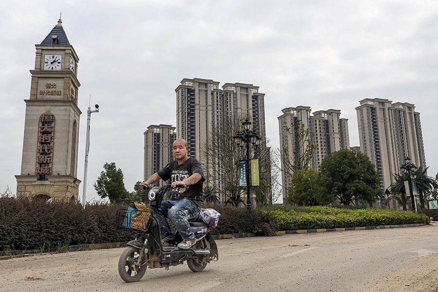 A man rides a scooter past a housing complex by Chinese property developer Evergrande in Wuhan, in China's central Hubei province on September 28, 2023. Beijing has recently taken some steps, like cutting mortgage rates, to this effect. But this does little to correct house prices or correct imbalances in the economy. Image AFP  / China OUT 