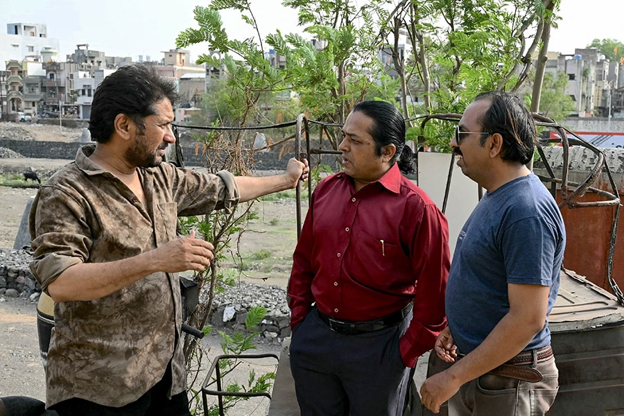 Amateur filmmaker Shaikh Nasir (L) speaks with actor Shaikh Aleemuddin Abdul Rasheed aka Aleem Tahir (C) and director Shaikh Muqeemuddin Abdul Rasheed aka Muqeem Meena Nagri. 
Image: Indranil Mukherjee / AFP©