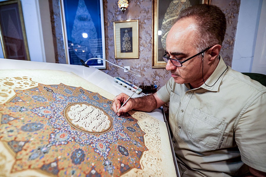 Mohammad Hossein Aghamiri, an artist who specialises in Persian miniatures, works on one of his pieces depicting al-Fatiha.
Image: Atta Kenare / AFP©