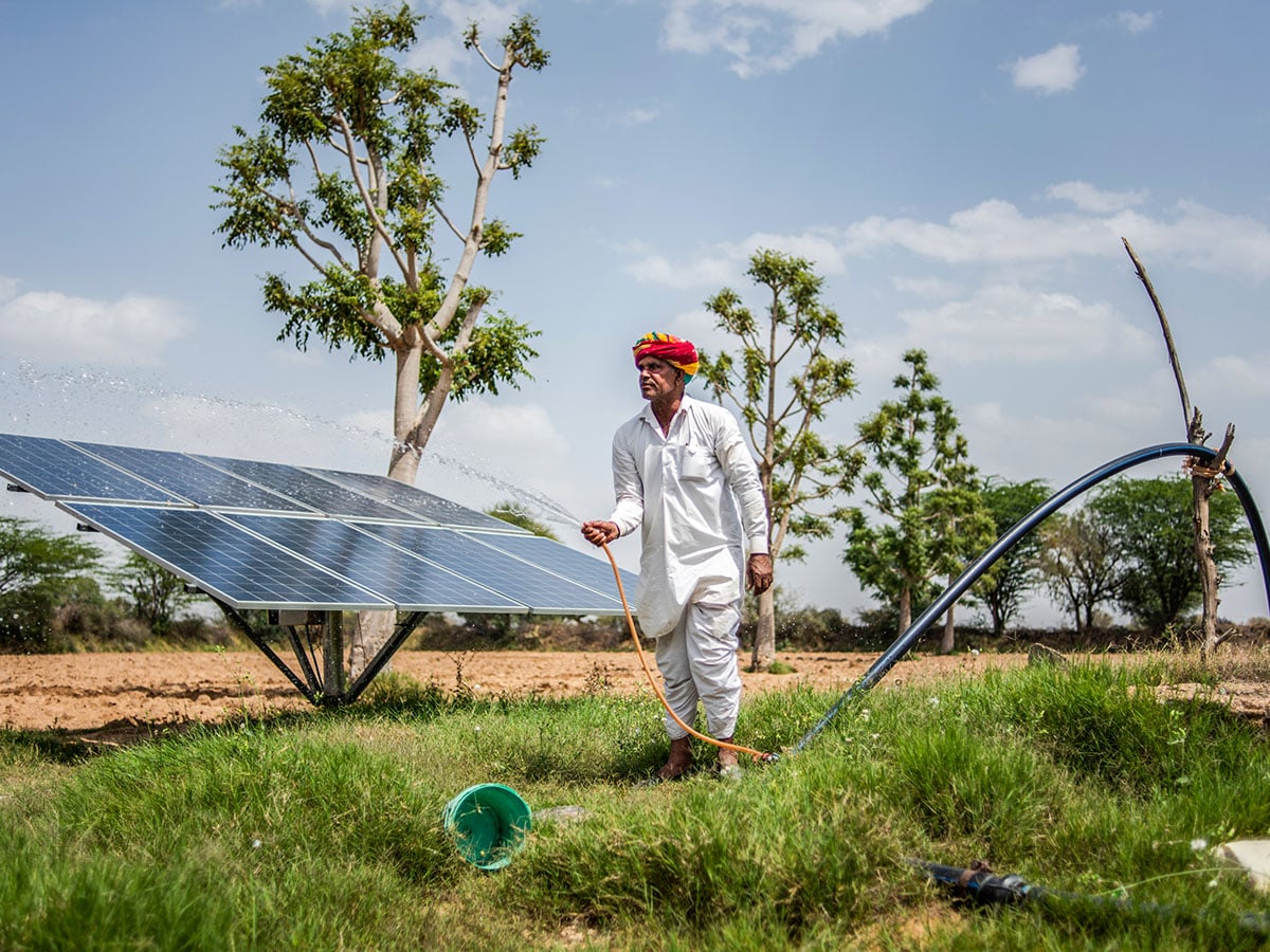 Indian farmer, cleans solar panels on his land, used to power a water pump and irrigation system for crops, in Solawata, Rajasthan, India. Image: Rebecca Conway/Getty Images 