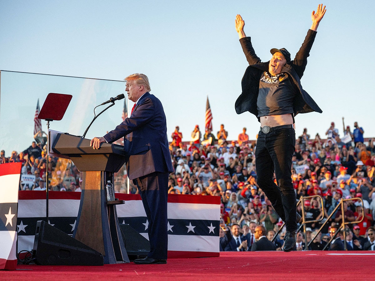 Tesla CEO Elon Musk (R) jumps on stage as he joins former US President and Republican presidential candidate Donald Trump during a campaign rally at site of his first assassination attempt in Butler, Pennsylvania, on October 5, 2024. Image:  Jim WATSON / AFP