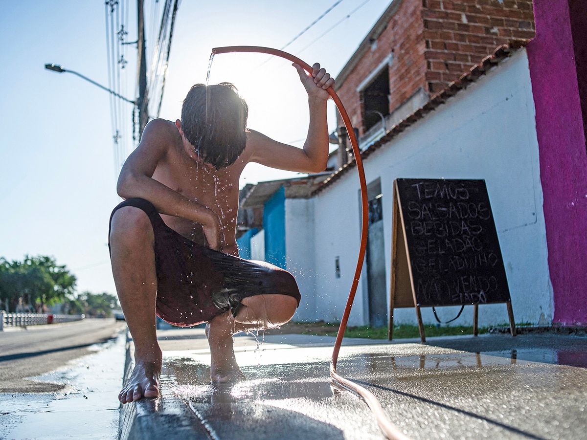 A boy cools off with a hose on the street amid a heat wave in the Guaratiba neighborhood of Rio de Janeiro, Brazil, on February 17, 2025. Rio de Janeiro residents and tourists were baking Monday in scorching temperatures as the city's crowded pre-Carnival street parties swung into full gear. 
Image: Terico Teixeira / AFP