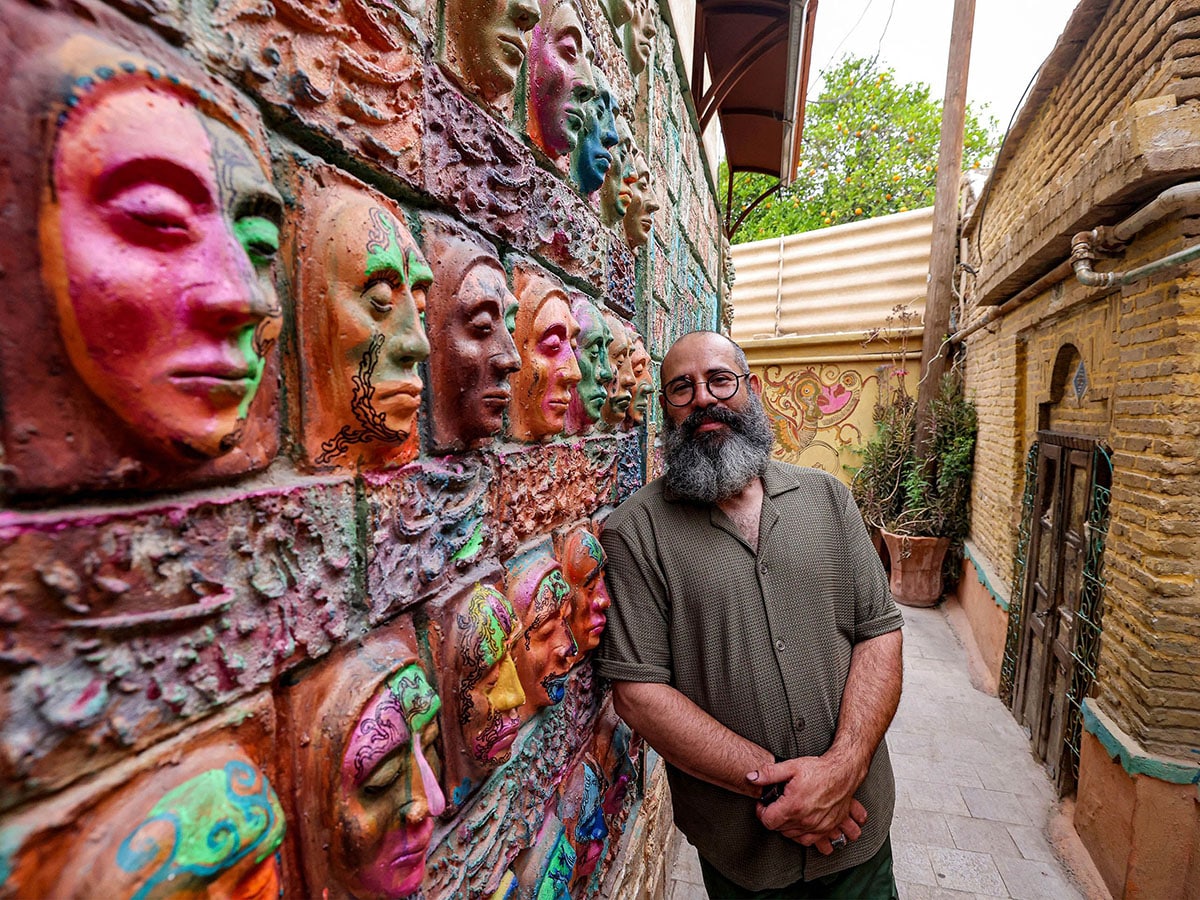 
Adel Yazdi, an Iranian artist who has transformed an alley in one of the old neighbourhoods of Shiraz into an open air permanent art gallery, stands next to one of his high reliefs in the central Iranian city. 
Image: Atta Kenare / AFP©