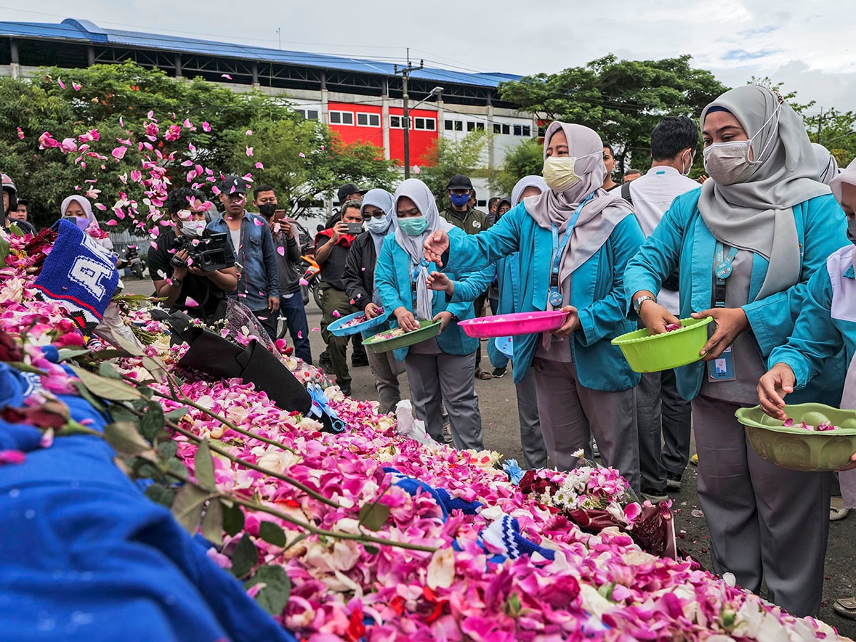 Supporters and people lay flowers as they pay condolence to the victims outside Kanjuruhan Stadium on October 03, 2022 in Malang, Indonesia. A riot and stampede broke out at a football stadium in East Java on Saturday. Police fired tear gas to disperse fans who had invaded the pitch and began fighting after the match ended. A stampede for the exits has resulted in at least 125 deaths, local media reports said, with many still injured in hospitals. 
Image: Ulet Ifansasti/Getty Images
