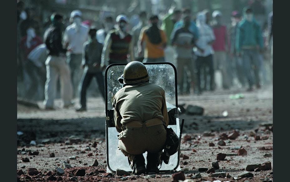 An Indian policeman holds a shield against stone-throwing Kashmiri protesters in Srinagar (September