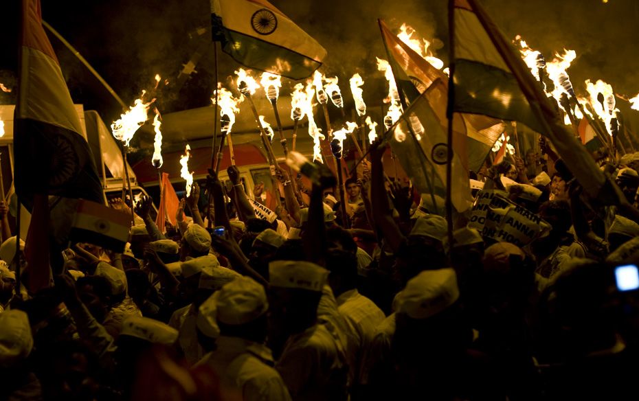 A procession of around 100 people hold torches and chant slogans outside the Ramlila ground in favou