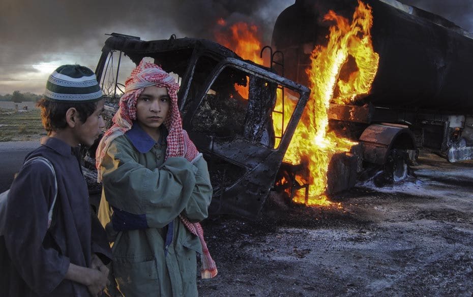 School boys stand near fuel trucks set ablaze in Pakistan's Baluchistan province on December 12.