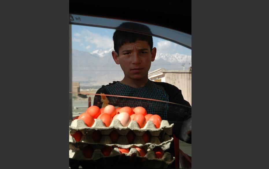 A boy selling boiled eggs at a fuel station. He has coloured them to make them look appetising. BTW,