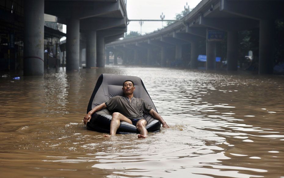 A man takes a nap on an inflatable sofa floating on a flooded street near the Yangtze River in China