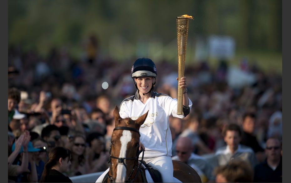 Zara Phillips holds the Olympic torch while riding through Cheltenham race course in Cheltenham     