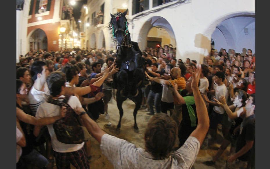 A rider rears up on his horse surrounded by a cheering crowd during the traditional Fiesta of San Jo