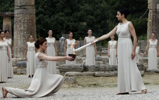 Greek actress Ino Menegaki (R), playing the role of High Priestess, lights the Olympic flame during 