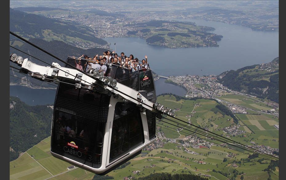 People wave during the inauguration trip of the world’s first open-air double-decker cable car