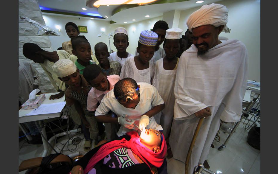 Dentist and CEO of Khartoum Dental Clinic Dr Fadil Elamin teaches oral hygiene to children and a she
