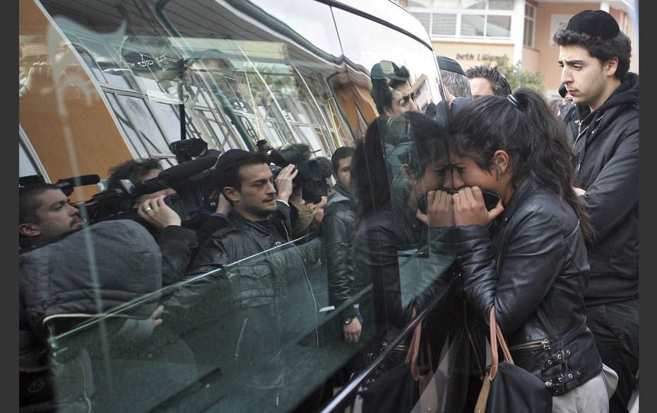 A young woman reacts near the hearse transporting the three coffins bearing the slain children from 