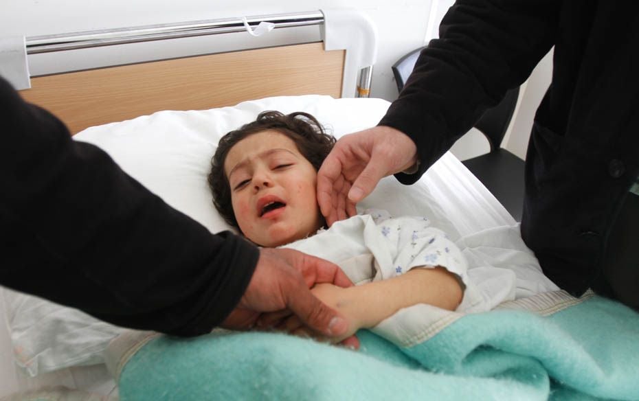 Nour al-Houda Idriss, a 4-year-old Syrian girl, lies on a bed as she is surrounded by her father and