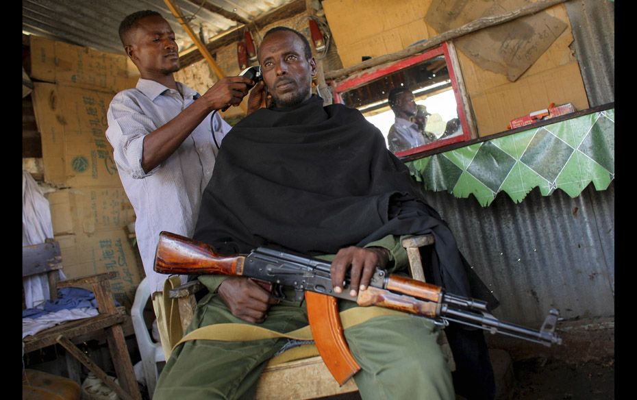 A fighter of the pro-government Ras Kimboni Brigade holds his weapon as he gets a haircut inside a b