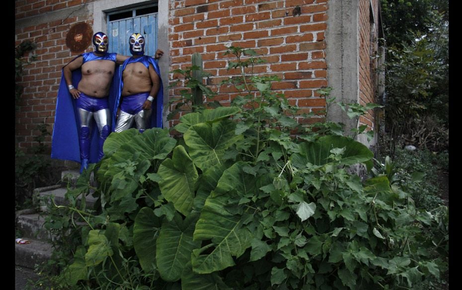 Residents dressed as wrestlers stand outside a house during festivities for Saint Michael the Archan