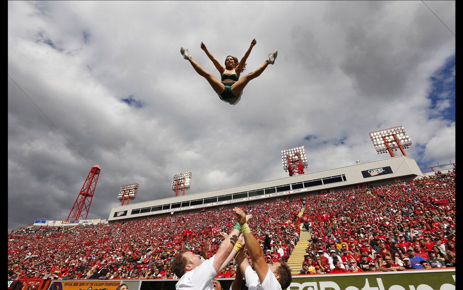 A member of the Edmonton Eskimos cheer squad flies through the air during the first half of their CF