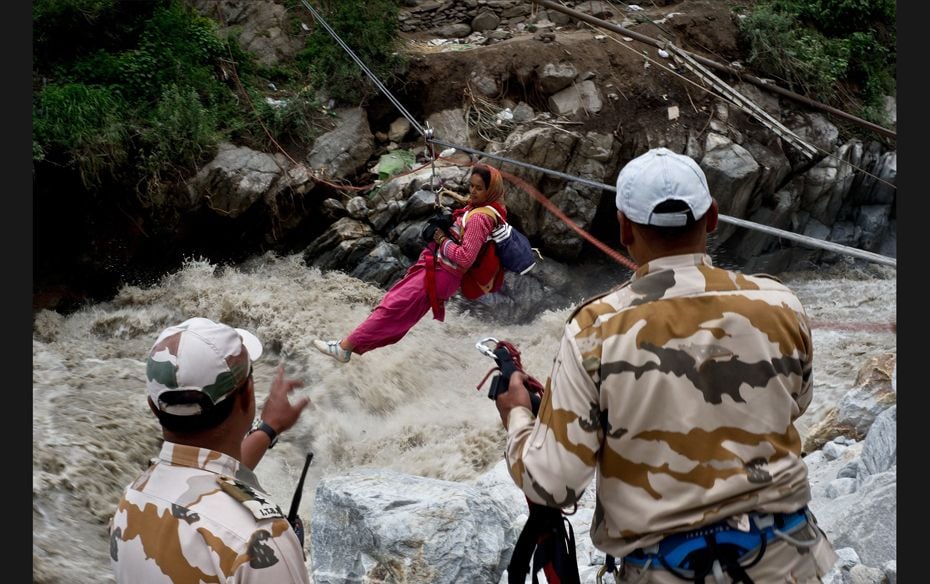 A stranded Indian pilgrim is transported across a river using a rope rescue system by Indo-Tibetan B