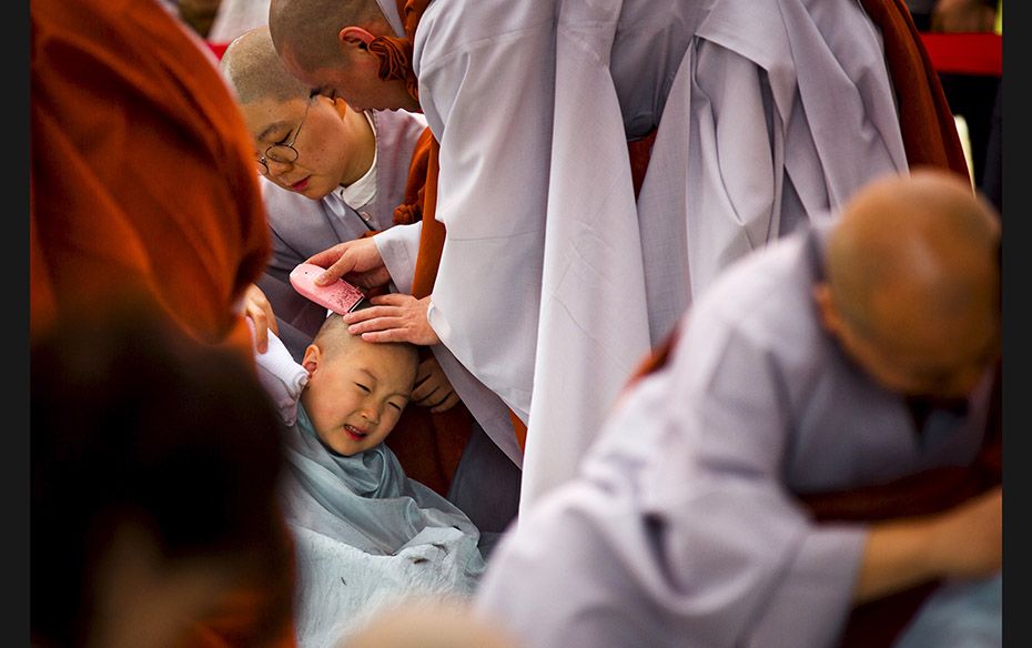 A Buddhist monk shaves the head of a novice monk during an inauguration ceremony at Jogye temple in 